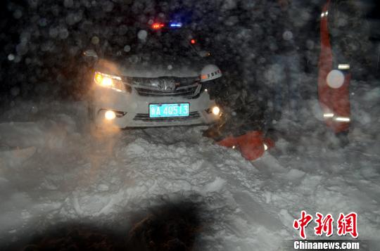 圖為消防人員跪在雪地里用鐵鍬鏟雪救援被困車輛?！±罱z